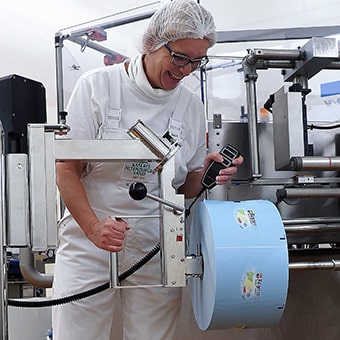 Grauhaarige Frau, die an einer Fabrikmaschine arbeitet